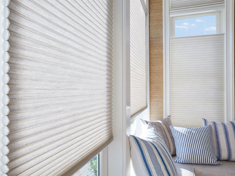 White window shades with light grey couch and blue and white pillows